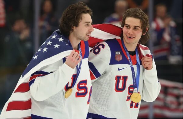 Jack and Quinn Hughes with their gold medals, draped in the American flag